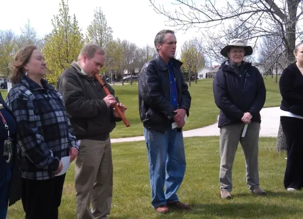 A group of Fox Valley Bahá’í members gathers outside, one of them playing a flute.